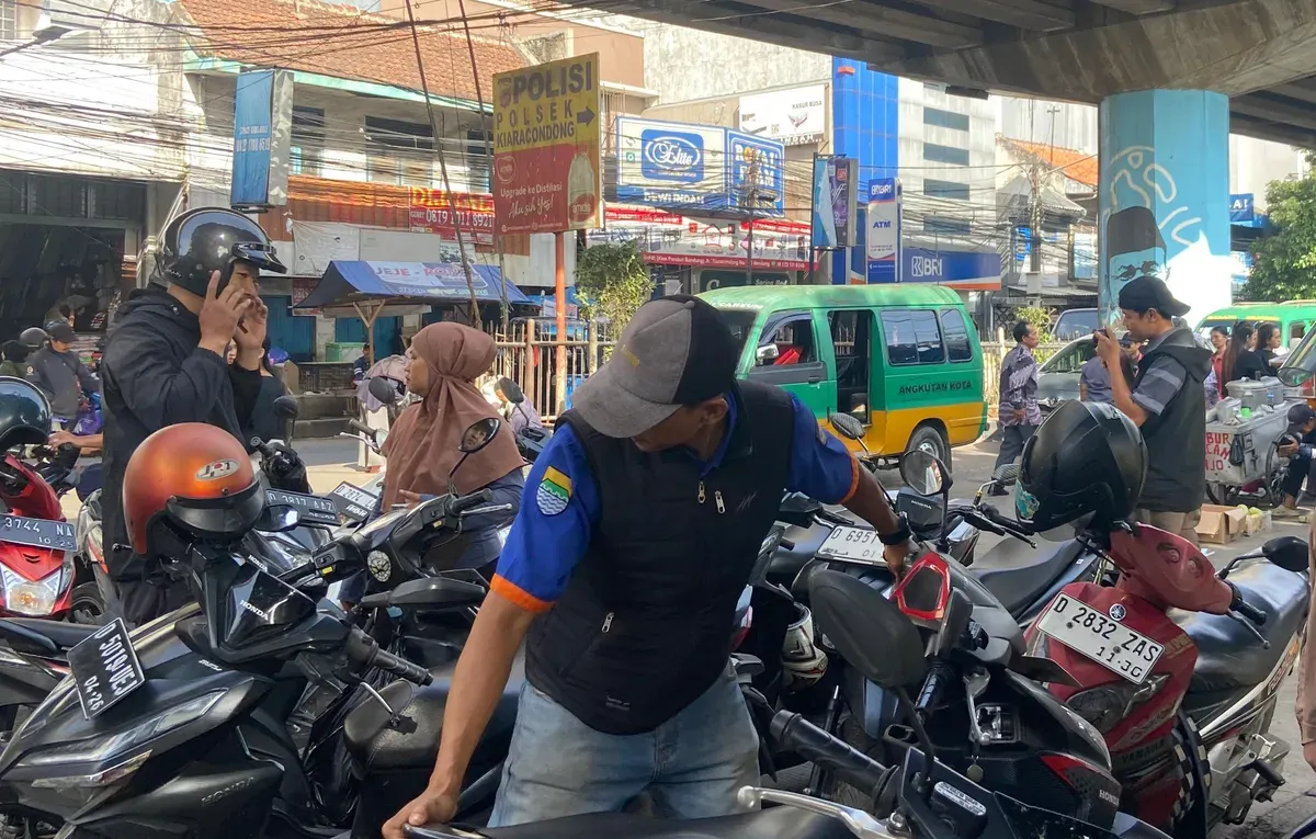 Seorang juru parkir yang sedang bertugas di Kiaracondong, Kota Bandung, Sabtu 29 November 2025 (Foto: AYOBANDUNG.ID/Asti Alya Anggraini)