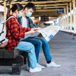 male-female-tourists-look-map-beside-railway-min