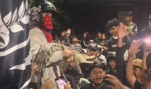 Seorang suporter membawa seekor buaya yang diikat ke tengah kerumunan saat nobar Derby Jawa Timur antara Persebaya Surabaya melawan Arema FC di Lapangan Kodikmar, Surabaya. (Foto: Screenshot TikTok @@alvinvin4973)